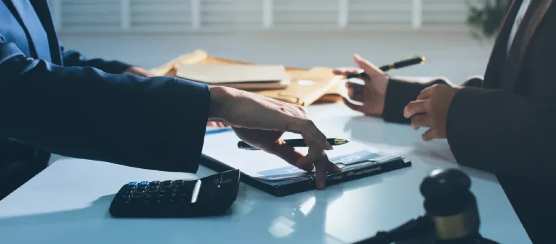 Two business people at a table with a calculator and pen